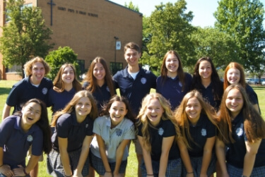 Group of smiling students in St. Pius X school shirts